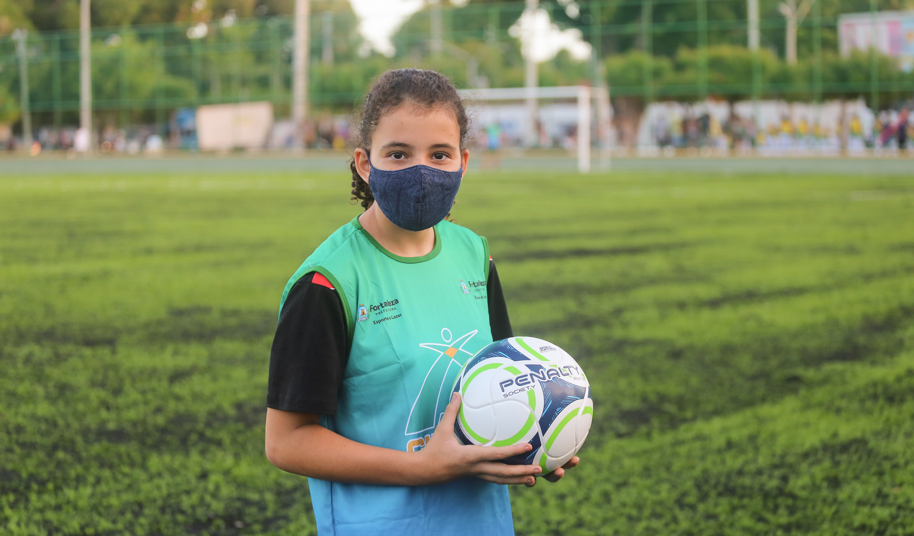 garota posa para a foto segurando uma bola de futebol